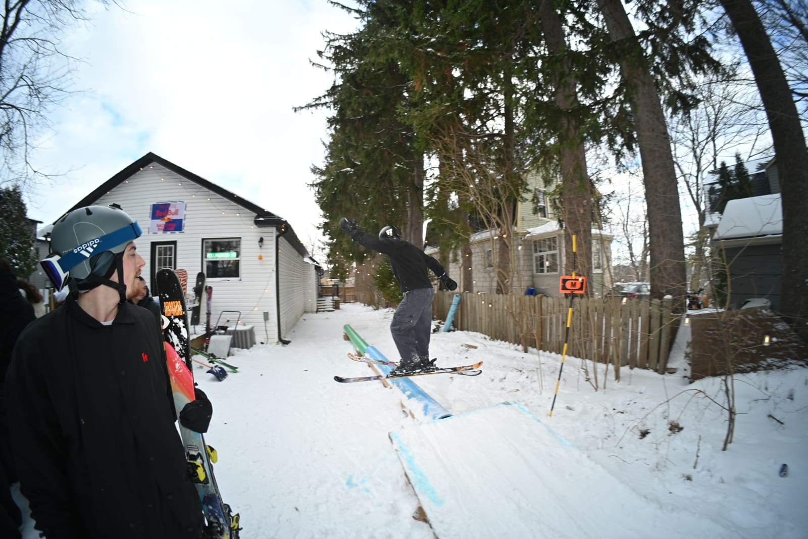 A skier sliding the backyard rail under the Red Bull Backyard Rail Jam banner