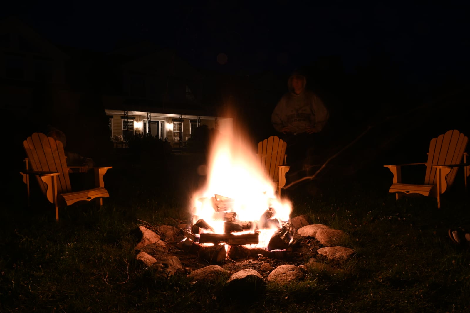Long exposure of the backyard firepit at night, chairs around the flames