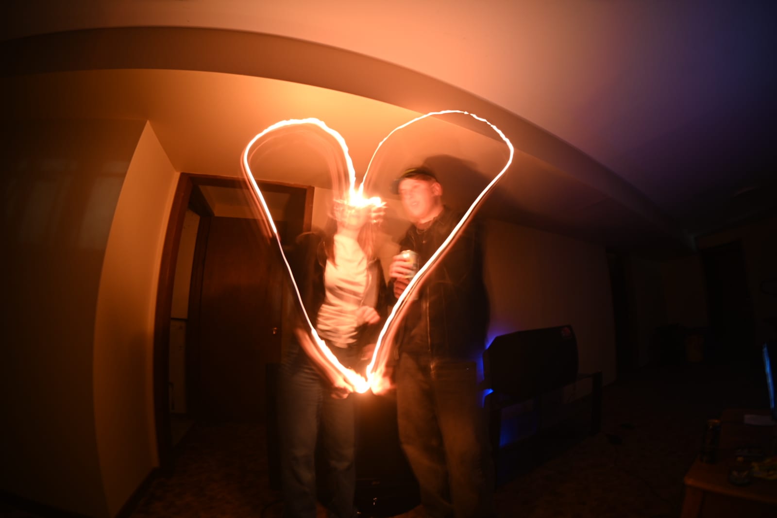Two people drawing a heart in the air with a light, caught in a long exposure