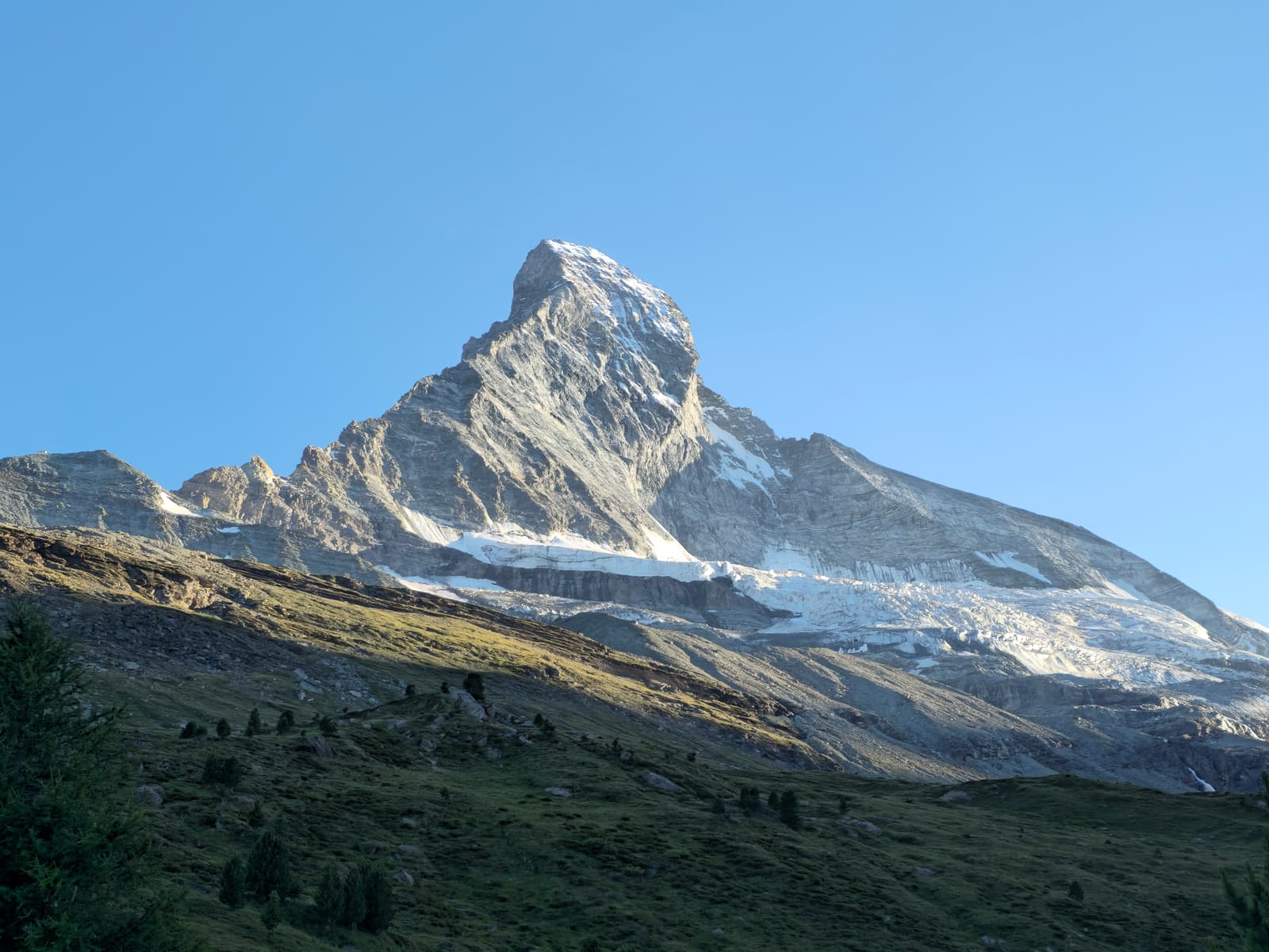 The Matterhorn lit by evening sun above a green slope outside Zermatt