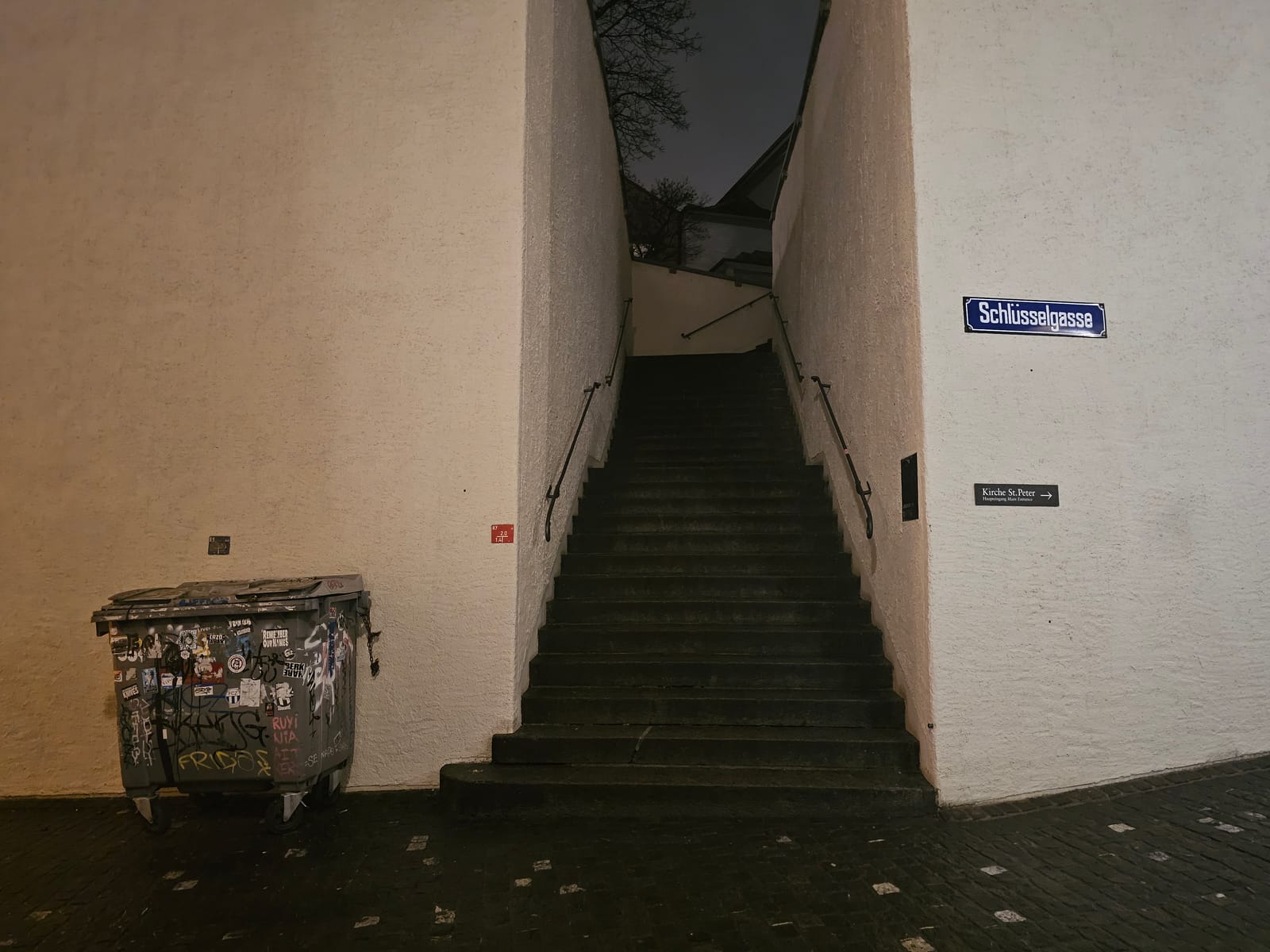 A narrow stone stairway off Schl&uuml;sselgasse at night, a sticker covered bin against the wall